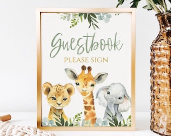 May include: A gold framed sign with a green and white watercolor illustration of a giraffe, lion, and elephant. The sign says "Guestbook Please Sign" in gold lettering.