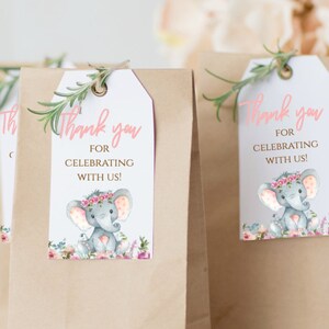 May include: Thank you for celebrating with us!  A pink and white favor tag with a watercolor illustration of a gray elephant wearing a pink flower crown. The elephant is surrounded by pink and white flowers.