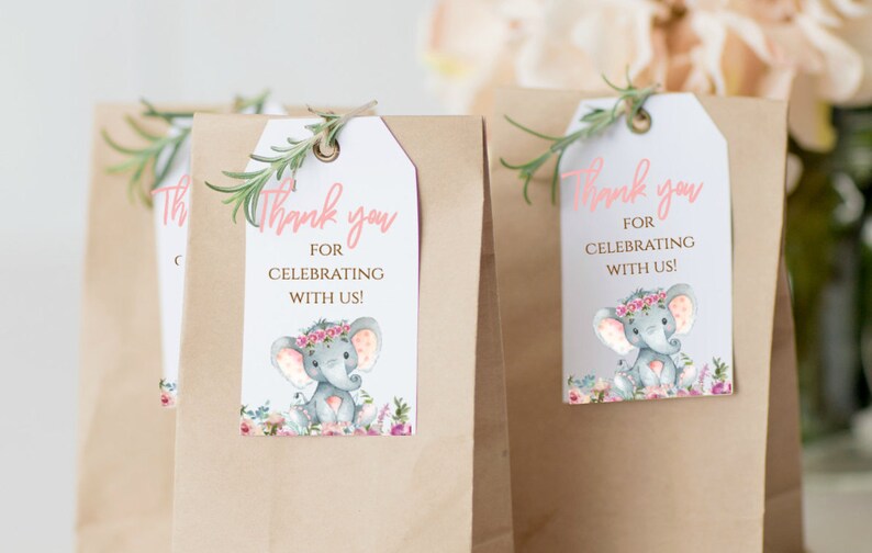 May include: Thank you for celebrating with us!  A pink and white favor tag with a watercolor illustration of a gray elephant wearing a pink flower crown. The elephant is surrounded by pink and white flowers.