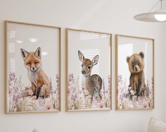 May include: A triptych of framed watercolour prints depicting a fox, a fawn, and a bear cub. The animals are set amongst lavender and pink wildflowers. The frames are made of light-coloured wood, creating a soft, natural aesthetic.