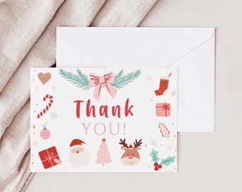 May include: A white Christmas-themed thank you card with a matching envelope. The card features a pink bow, Christmas tree, Santa, reindeer, and the words "Thank You!" in red. Other illustrations include a stocking, gift, and candy cane.