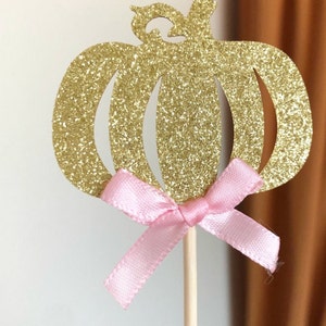 May include: Gold glitter pumpkin cupcake topper with a pink ribbon bow.  Matching decorations available.