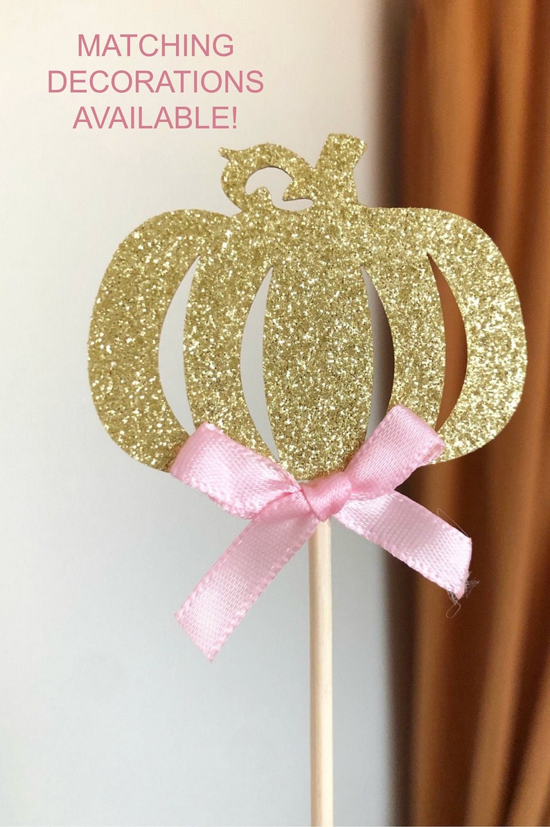 May include: Gold glitter pumpkin cupcake topper with a pink ribbon bow.  Matching decorations available.