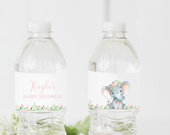 Può includere: Due bottiglie d'acqua in plastica trasparente con etichette. Un'etichetta ha un motivo floreale rosa e il testo "Baby Shower di Kayla". L'altra etichetta ha un'illustrazione ad acquerello di un elefante grigio con una corona floreale rosa e pois rosa.