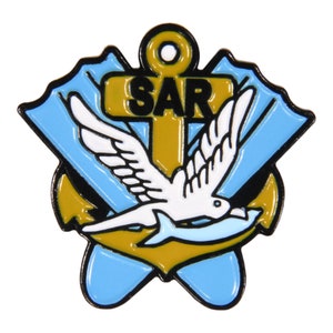 May include: A gold anchor with a white dove carrying a fish in its beak. The anchor has the letters "SAR" on the crossbar. The dove and fish are surrounded by two blue wings.