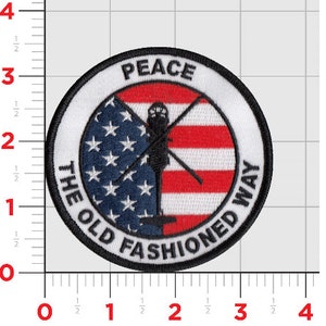 May include: A round, white patch with a black border and the text "PEACE THE OLD FASHIONED WAY" around the edge.  The center of the patch features a red, white, and blue American flag with a silhouette of a helicopter.