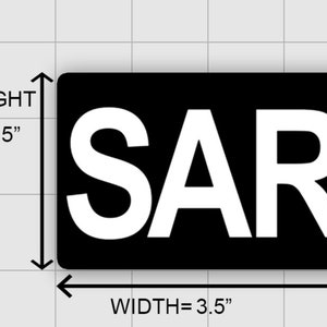 May include: Black rectangular patch with white letters spelling "SAR". The patch measures 3.5 inches wide and 2.15 inches high.