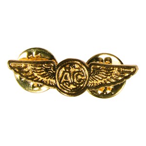 May include: Gold-colored Air Traffic Controller wings with the letters ATC in the center. The wings are attached to two round pins.
