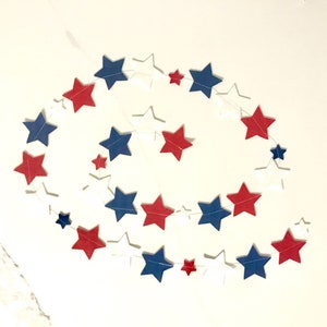 May include: A red, white, and blue star garland with alternating colors. The garland is made of paper stars and is strung together with white thread.