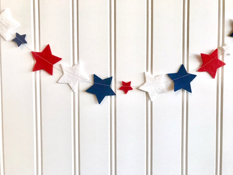 May include: A red, white, and blue felt star garland. The garland is made of felt stars in red, white, and blue, and is strung together with white thread.