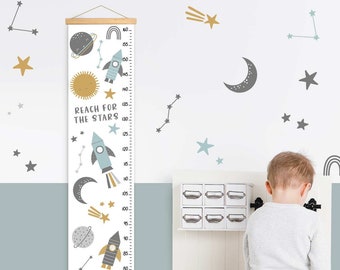 May include: A height chart with a space theme, featuring rockets, planets, stars, and the text "Reach for the Stars." The chart is white with a wooden frame and measures up to 160 inches. Decorative wall stickers of stars and planets are also visible.