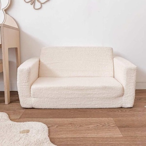 Può includere: Un divano bianco in pelliccia sintetica con una texture morbida e soffice. Il divano è perfetto per la camera da letto di un bambino o una sala giochi.