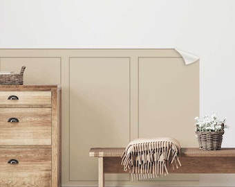 May include: A wooden bench with a beige throw blanket sits in front of a wall with a beige wainscoting design. A wooden dresser with three drawers is on the left side of the image. A wicker basket with a plant is on the right side of the image.
