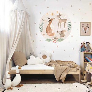 May include: A white canopy bed with a brown blanket and a white cloud-shaped pillow. The wall behind the bed has a round sticker with a fox, deer, and squirrel in a forest scene. The wall also has brown polka dots.