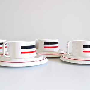 May include: Set of four white ceramic teacups and saucers with red and black stripes.