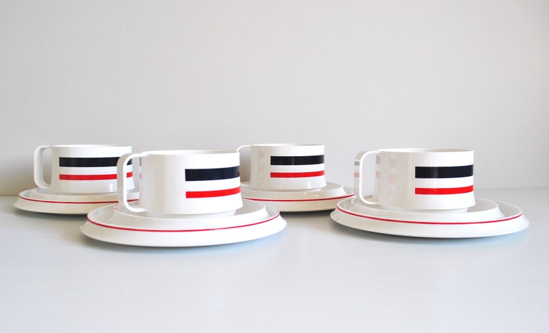 May include: Set of four white ceramic teacups and saucers with red and black stripes.