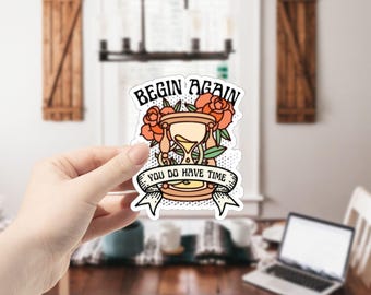 May include: A sticker with an hourglass surrounded by flowers and the text "Begin Again You Do Have Time".