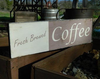Könnte beinhalten: Ein rustikales Holzschild mit weißer und brauner Farbe. Das Schild trägt die Aufschrift "Fresh Brewed Coffee" in handschriftlicher Schrift.