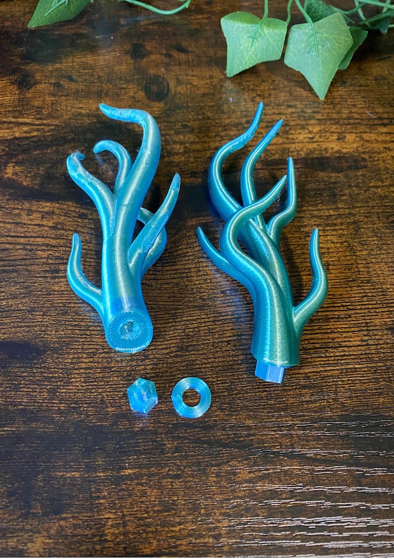 Peut inclure: Deux sculptures en forme d'arbre de couleur teal avec de multiples branches incurv&eacute;es. Les sculptures sont imprim&eacute;es en 3D et pr&eacute;sentent un effet d&eacute;grad&eacute;, passant du bleu au vert. Sont &eacute;galement inclus un petit cube et un anneau, tous deux de couleur teal assortie.