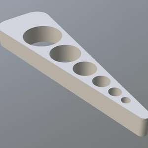 Puede incluir: Una herramienta triangular de color beige claro con una serie de agujeros circulares graduados. La herramienta tiene un extremo redondeado y se estrecha hasta un punto, con agujeros de tamaño decreciente. El objeto está renderizado en 3D.