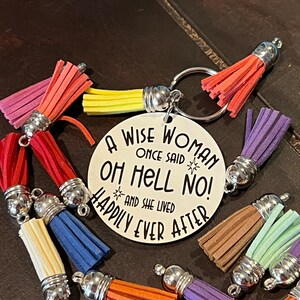 May include: A silver keychain with a round tag that reads "A wise woman once said Oh Hell No! And she lived happily ever after". The keychain has a variety of colorful tassels attached to it.