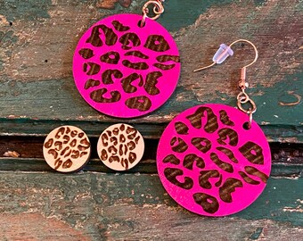 Op de afbeelding: Een set ronde houten oorbellen met een roze en bruine luipaardprint. De grotere oorbellen hebben een haaksluiting, terwijl de kleinere oorbellen studs zijn.