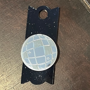 May include: A black and silver disco ball keychain with a hole for a key ring.