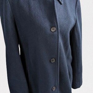 May include: A dark blue wool coat with a collar and four buttons down the front.
