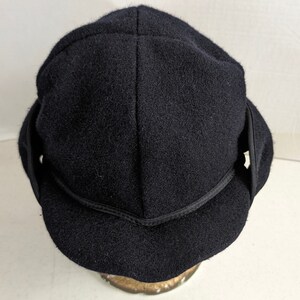 May include: A black wool hat with a wide brim and ear flaps. The hat has a simple design and is made of a soft, warm material.