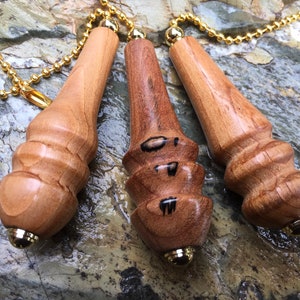 May include: Three wooden light pull chains with gold metal ends. The chains are made of small, round, gold beads. The wooden pulls are all different shades of brown and have a unique, hand-carved design.