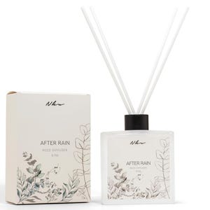 May include: A square glass reed diffuser bottle with a black cap and three white reeds, accompanied by a matching rectangular cardboard box. Both feature the text "Nkw" and "AFTER RAIN REED DIFFUSER 6.7oz" with a botanical illustration of green leaves.