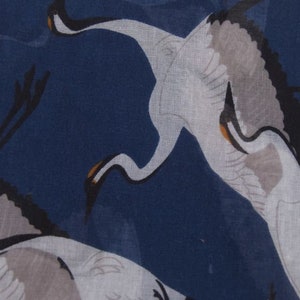 May include: A navy blue fabric with a white crane pattern. The crane is in flight with its wings spread out. The fabric has a soft, flowing texture.