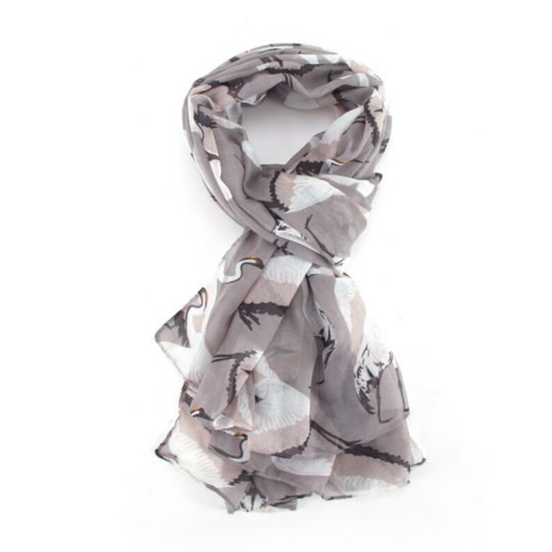 May include: A gray scarf with a white crane print. The scarf is made of a lightweight fabric and is perfect for adding a touch of style to any outfit.