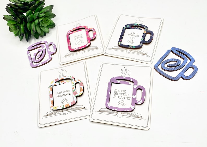 May include: Five different coffee mug shaped bookmarks with various floral and patterned designs. Each bookmark has a different quote about coffee and reading. The bookmarks are on a white background.