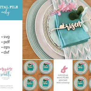 May include: Five wooden Easter place card holders with a bunny silhouette and the words "risen", "christ", "king", "lamb", and "glory" in a light wood color. The place cards are on a blue and white patterned napkin and a white plate with a blue and white patterned rim. The place cards are surrounded by pink flowers.