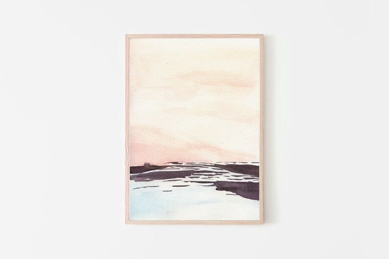 Peut inclure: Une peinture &agrave; l'aquarelle encadr&eacute;e d'un paysage avec un ciel rose et orange et un premier plan bleu fonc&eacute; et gris. La peinture est dans un cadre en bois clair.