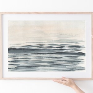 Puede incluir: Una pintura de acuarela enmarcada de un paisaje mar&iacute;timo en una gama de colores azul claro y gris. La pintura representa un horizonte con un cielo azul claro y un mar azul oscuro con pinceladas horizontales.
