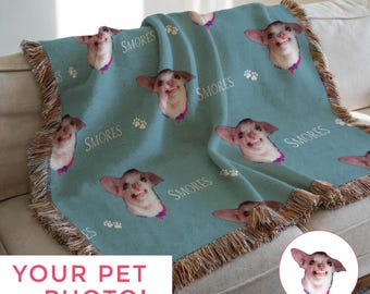 May include: Teal throw blanket featuring a repeating pattern of a smiling dog's face, paw prints, and the word "S'mores" in white. The blanket has a fringed edge and is draped over a sofa. The text "YOUR PET PHOTO!" is at the bottom.