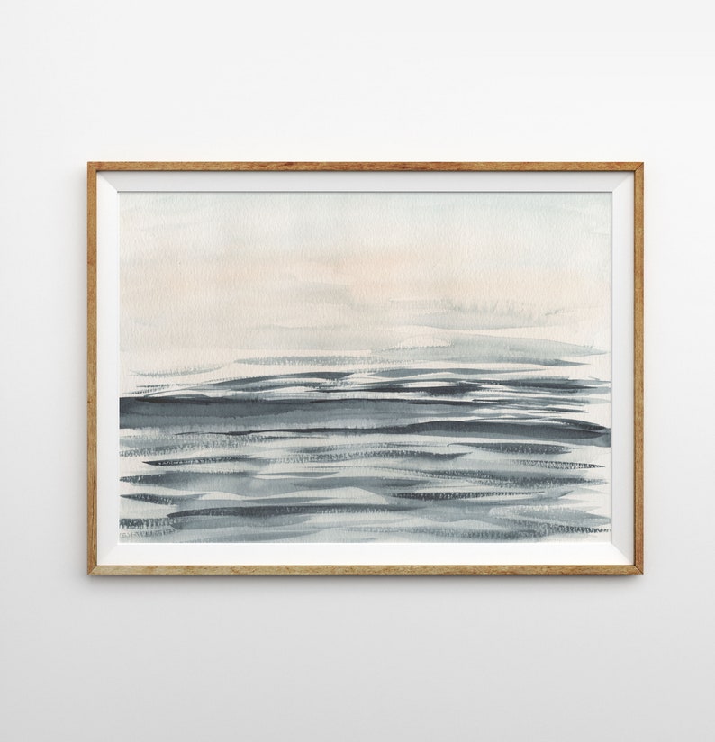 Puede incluir: Una pintura de acuarela enmarcada de un paisaje mar&iacute;timo con colores suaves y apagados. La pintura presenta un cielo azul claro con un toque de rosa y un oc&eacute;ano azul oscuro con olas sutiles.