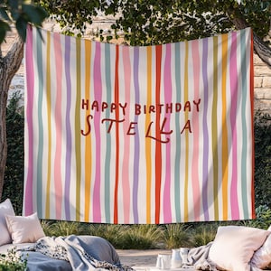 May include: A colorful birthday banner with vertical stripes in various colors, including pink, yellow, and green. The words "HAPPY BIRTHDAY STELLA" are written in a brown, handwritten-style font.