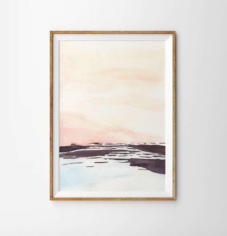 Peut inclure: Une peinture &agrave; l'aquarelle d'un paysage avec un ciel rose et orange et un premier plan violet fonc&eacute;. La peinture est encadr&eacute;e dans un cadre en bois clair.