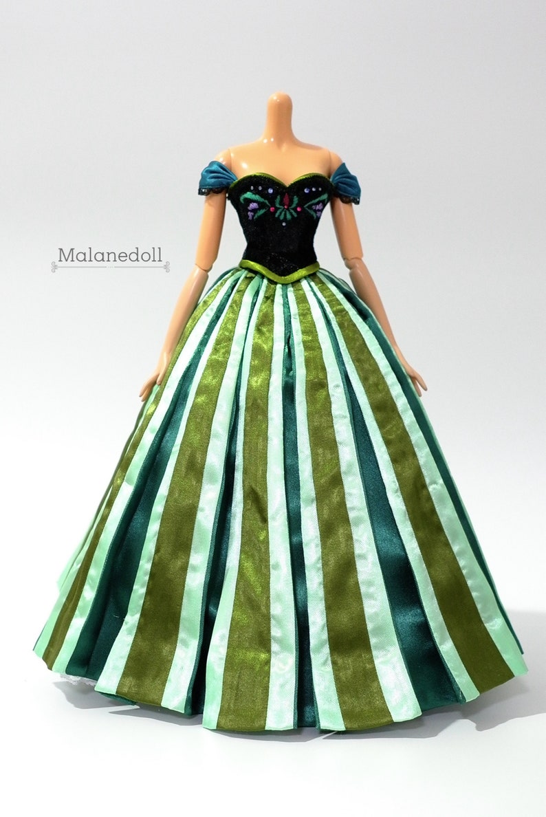 May include: A green and white striped ball gown with a black bodice featuring embroidered details. The bodice has a sweetheart neckline and off-the-shoulder straps.