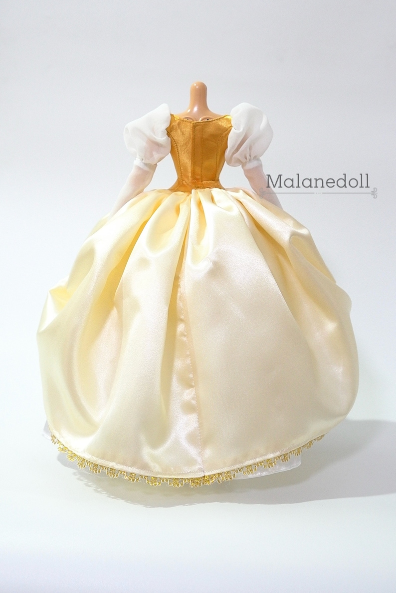 May include: A white satin ball gown with a gold bodice and white puffed sleeves. The gown has a gold trim around the bottom.