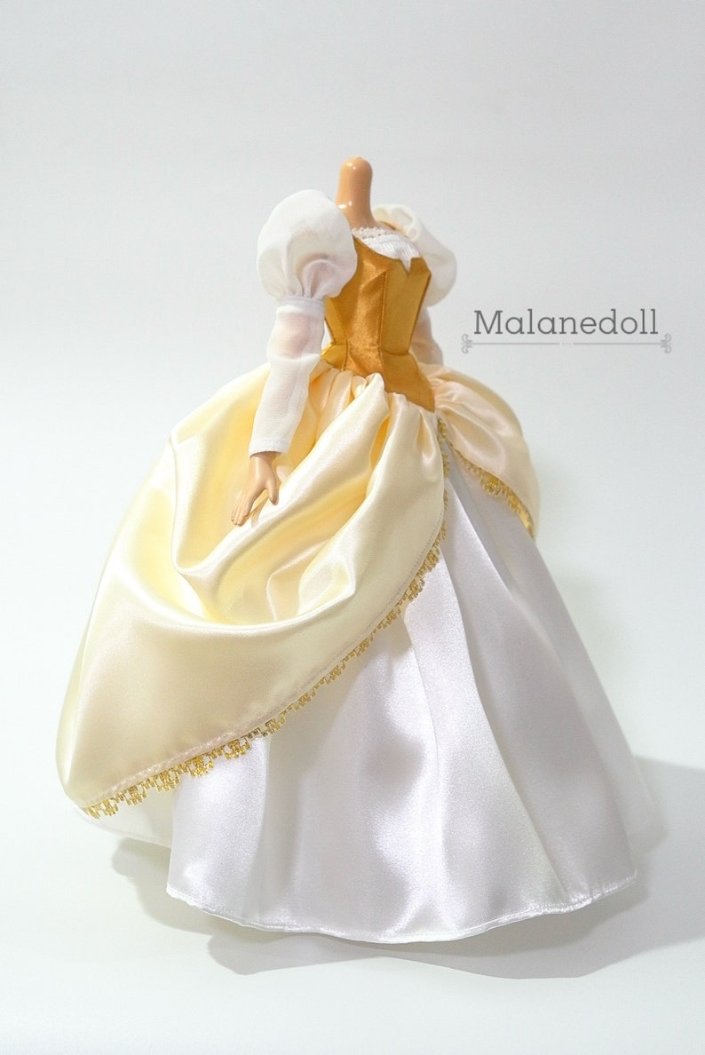 May include: A white and gold satin ball gown with a gold bodice and puffed white sleeves. The gown has a gold trim around the bottom.