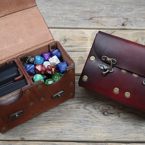 La boîte de combat ! Grande boîte de rangement en cuir avec rangement pour les dés. Options de personnalisation pour la conception et la mise en page. Plusieurs couleurs disponibles !