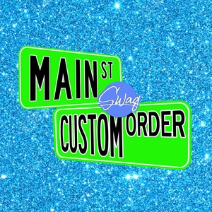 May include: Green and black sign with the text "Main St Swag Custom Order" on a blue glitter background.