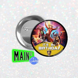 May include: A round button with a silver backing and a colourful graphic featuring characters from the Guardians of the Galaxy movie. The button has the text "IT'S MY BIRTHDAY" and the Guardians of the Galaxy logo. A green street sign that says "MAIN ST" is also in the image.