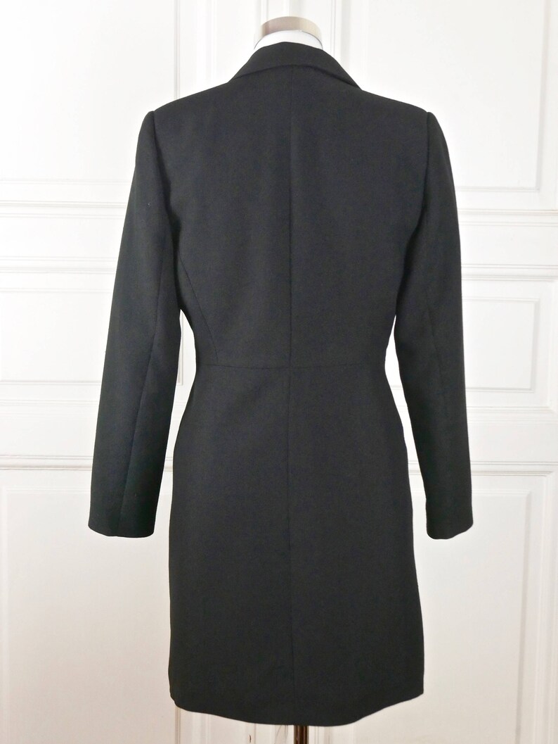 May include: A black long-sleeved blazer with a classic collar and a single-breasted closure. The blazer has a fitted silhouette and a straight hem.