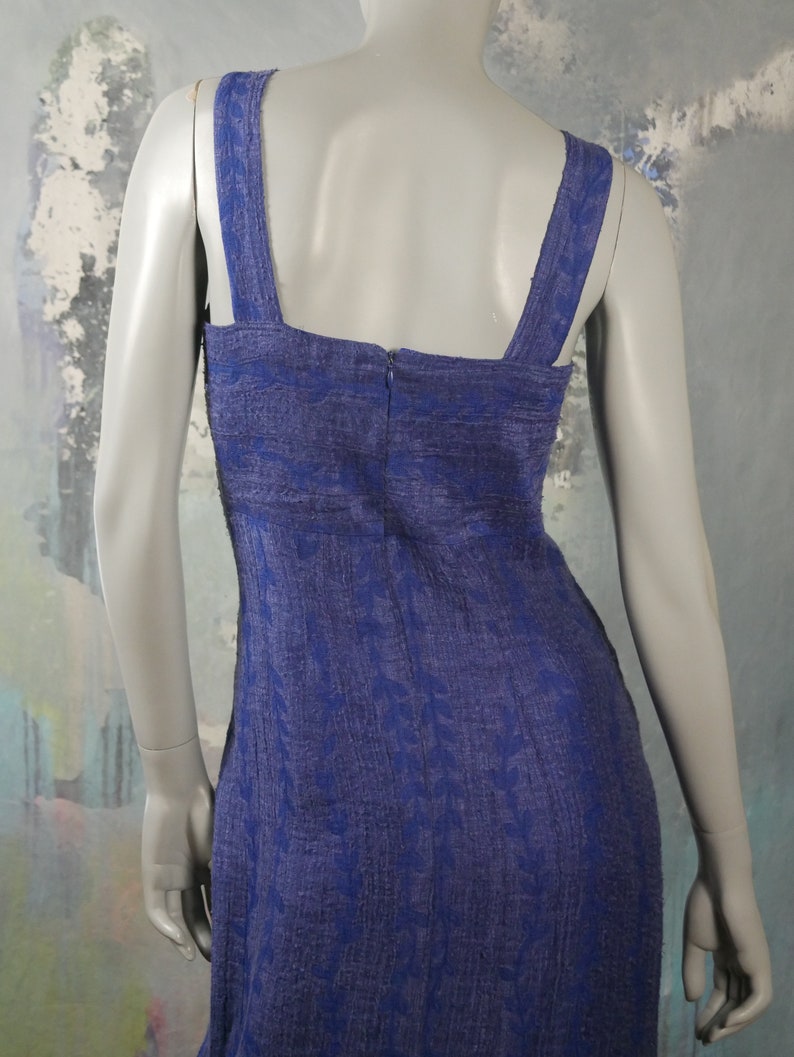 May include: A blue sleeveless dress with a floral pattern. The dress has a square neckline and a zipper in the back.