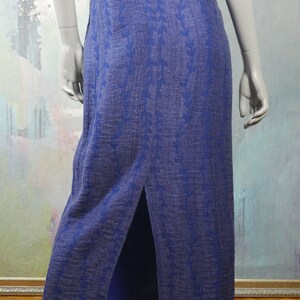 May include: A long, blue maxi dress with a floral pattern. The dress has a slit up the back and is made of a soft, flowing fabric.